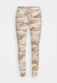 Beige camoufloaged jogger-housut, joissa on elastinen vyötärö, nyöri ja kaksi sivutaskua. Materiaali näyttää pehmeältä ja sileältä.