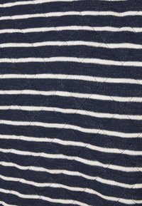 Tessuto a maglia con strisce diagonali alternate blu navy e bianche, caratterizzato da un motivo testurizzato e in rilievo.