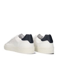 Witte leren sneakers met een gestructureerde afwerking, met een contrasterende zwarte hieltab en een dikke, gestructureerde witte zool.