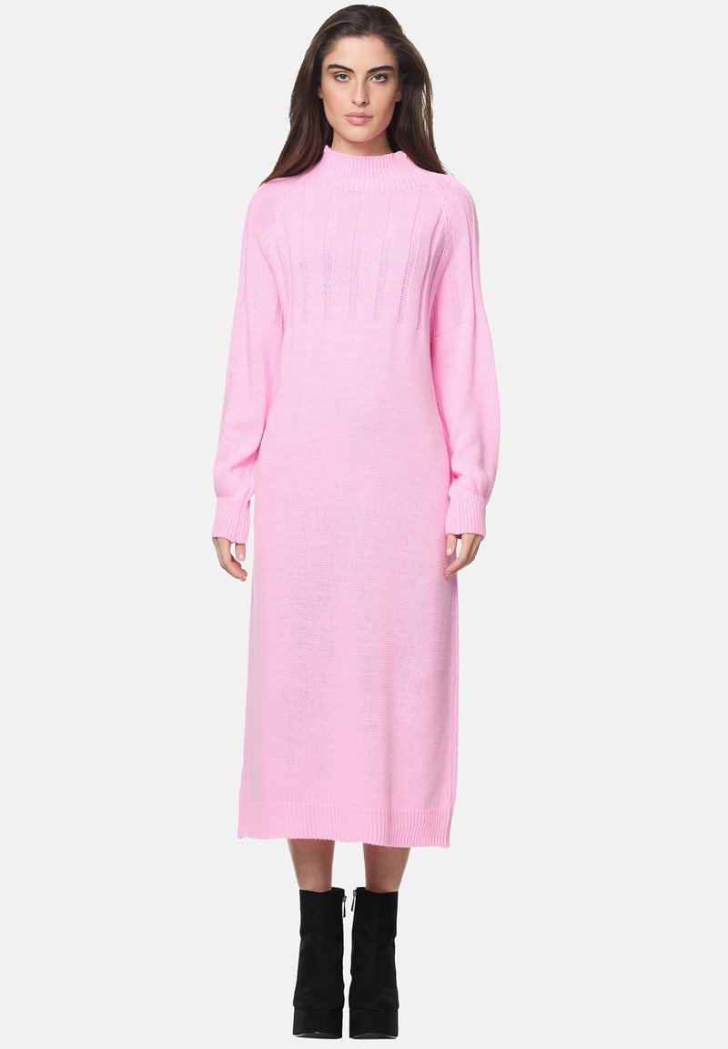 Vestito a maniche lunghe con collo alto in morbido tessuto a maglia rosa, caratterizzato da dettagli a coste e silhouette dritta, abbinato a stivali neri con tacco.