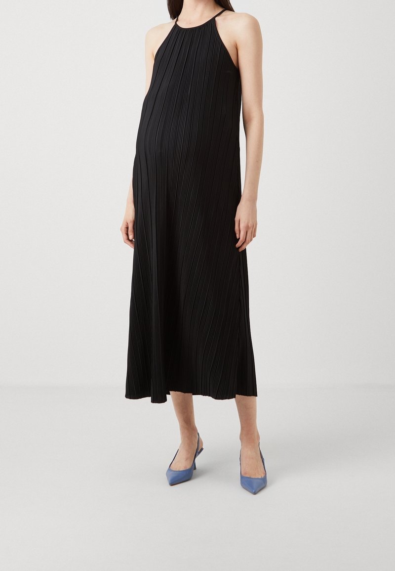Czarna, plisowana maxi sukienka z dekoltem w kształcie halter, o luźnym kroju. Noszona z niebieskimi czółenkami w szpic.
