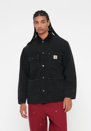 Schwarze Jeansjacke mit leicht lockerem Schnitt, ausgestattet mit zwei Fronttaschen, silbernen Knöpfen und einem Kragen. Logopatch auf der linken Brust.