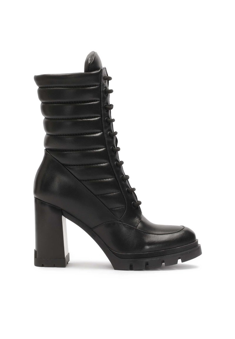 Botín negro de cuero hasta el tobillo con parte superior acanalada, cierre de cordones en la parte delantera y tacón cuadrado robusto. Presenta una puntera redondeada y detalles texturizados.