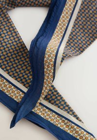 Seidenschal mit marineblauem Rand und geometrischem Muster mit kleinen goldenen und weißen kreisförmigen Motiven auf weißem Hintergrund.