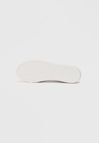 Witte sneakerzool met een gestructureerd rasterpatroon, plat weergegeven op een effen witte achtergrond.