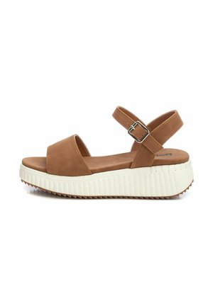 Sandalias de plataforma de ante marrón con punta abierta, correa para el tobillo ajustable y una suela de goma blanca texturizada con un patrón de ola.