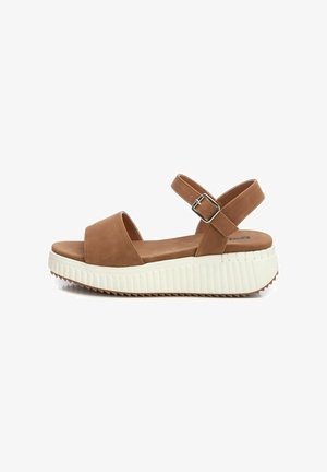 Sandalias de plataforma de ante marrón con punta abierta, correa para el tobillo ajustable y una suela de goma blanca texturizada con un patrón de ola.