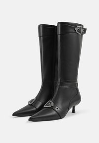 Black leather knee-high boots with a pointed toe, silver buckle accents, slim heel, and zipper closure along the inner side.