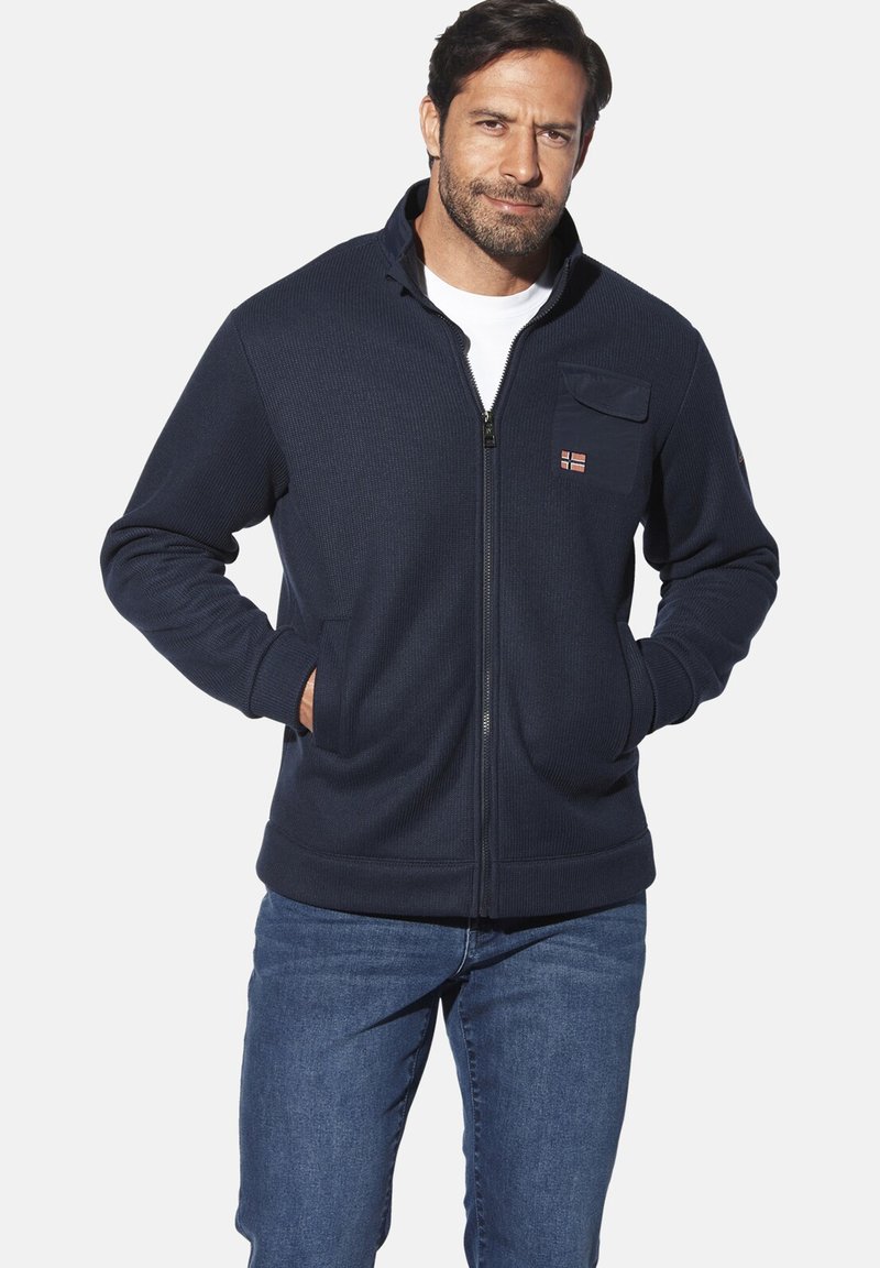 Dunkelblaue Fleecejacke mit durchgehendem Reißverschluss, hohem Kragen, Brusttasche mit Reißverschluss und Seitentaschen. Gerippte Bündchen und Saum sorgen für Struktur.