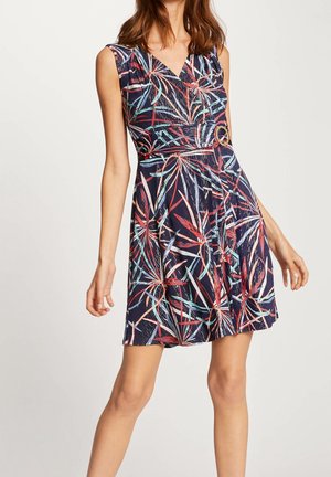 Granatowa sukienka z kolorowym wzorem liści, bez rękawów, z dekoltem w serek i talią zebrą; zdobiona okrągłym akcentem w talii.