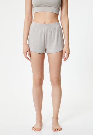 Pantalones cortos gris claro con una cintura elástica, hechos de tejido suave. Presentan un corte holgado y costuras mínimas para mayor comodidad.