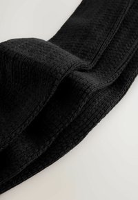 Sort strikket tørklæde med et tekstureret, ribbet mønster. Materialet ser blødt og fleksibelt ud, med pænt afsluttede kanter.