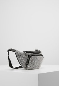 Marsupio in sequins argento con chiusure a zip nere e cinturino regolabile, caratterizzato da una forma sinuosa e una superficie testurizzata.