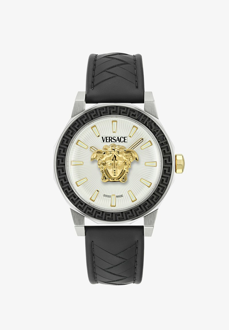 Versace kell, millel on hõbedane oktaedrine korpus, must bezel, valge tekstureeritud kellapind, kuldne Medusa logo ja must nahkrihm, millel on õmblused.