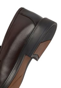 Scarpa da uomo in pelle marrone scuro con suola in gomma nera e marrone texturizzata, con cuciture dettagliate nell'area del tallone.