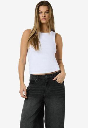 Top sin mangas blanco con relieve combinado con pantalones negros de cintura alta y pierna ancha. El top tiene un escote redondo y una silueta ajustada.