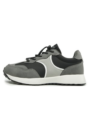 Chaussure de sport grise et noire avec un design en matériaux mixtes, surfaces lisses et texturées, fermeture à lacets et semelle extérieure en caoutchouc.