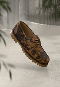Sapatilha de barco em camuflagem castanha com parte superior em tecido texturizado, fecho de atacadores e sola de borracha com pequenos relevos para tração.