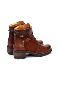 Brown leather and suede ankle boots feature a rounded toe, lace-up front, and chunky heel with a textured sole for traction.