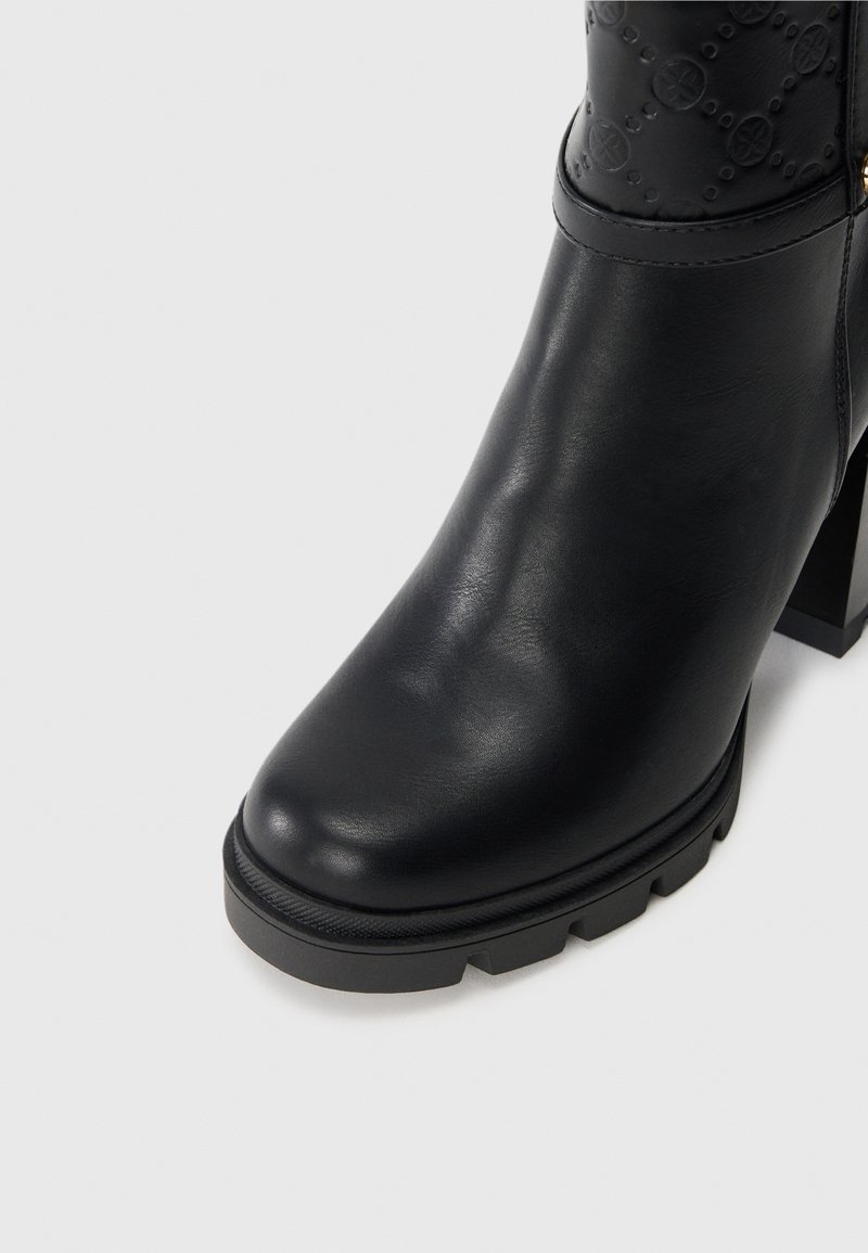Stivale alla caviglia in pelle nera con upper texturizzato, tacco a blocco, punta arrotondata e suola in gomma spessa. Presenta un delicato motivo in rilievo sulla parte superiore.