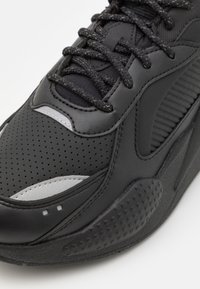 Svart atletisk sneakers i teksturert lærøvre, med perforerte detaljer, tonale snører, gummisåle og reflekterende detaljer.