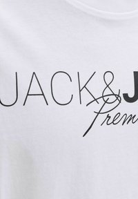 White fabric with black text reading "JACK & J Premium" in a mix of simple and cursive fonts.