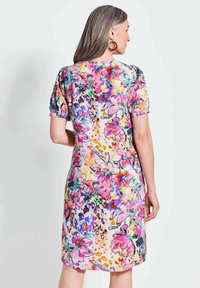 Blumenkleid mit kurzen Ärmeln, das eine Mischung aus Rosa, Lila und Gelbtönen zeigt. Hergestellt aus einem leichten, glatten Material mit einem bunten Muster.
