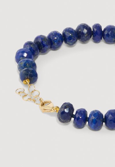 Pulsera de cuentas de lapislázuli con piedras azules facetadas y lisas, que presenta un cierre de metal en tono dorado y una cadena extensora.