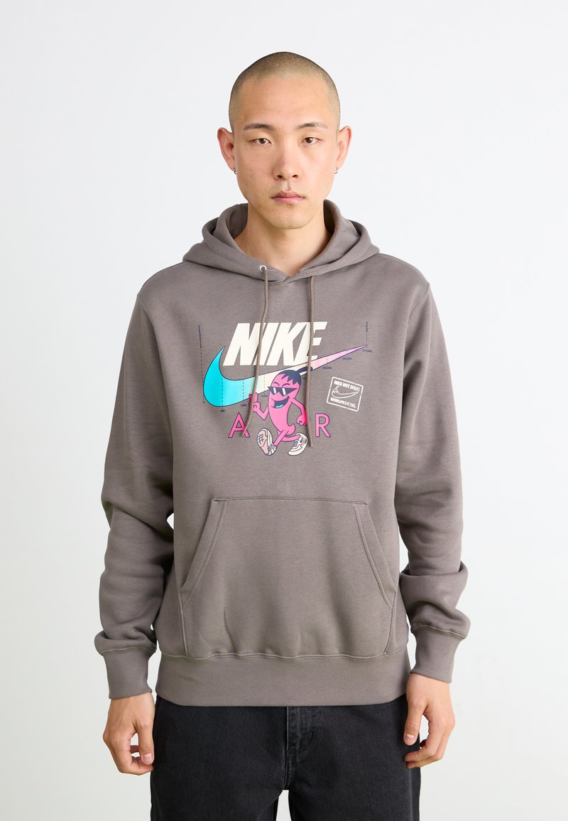 Grå hættebluse med lomme foran, der har et farverigt Nike-logo og en tegneserie-grafik. Blødt fleece-materiale med ribbede manchetter.