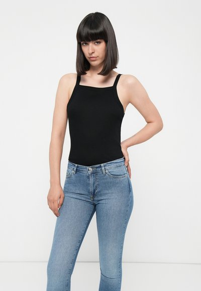 Bodysuit sans manches noir avec décolleté carré, associé à un jean slim bleu clair. Tissu lisse et extensible ; coupe décontractée.