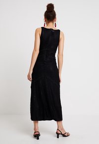 Černé krajkové maxi šaty s propracovaným květinovým vzorem, bez rukávů a s přiléhavým živůtkem. Hladká textura a volný silueta.