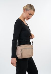 Beige læder crossbody taske med sølvhardware, frontlynlåslommer og justerbar rem. Glat tekstur, kompakt design og minimal udsmykning.