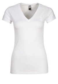 Bílý, kratičký tričko s krátkým rukávem ve výstřihu do V, vyrobené z bavlny. Má přiléhavý střih a malé logo na levé části hrudi. Měkká textura.
