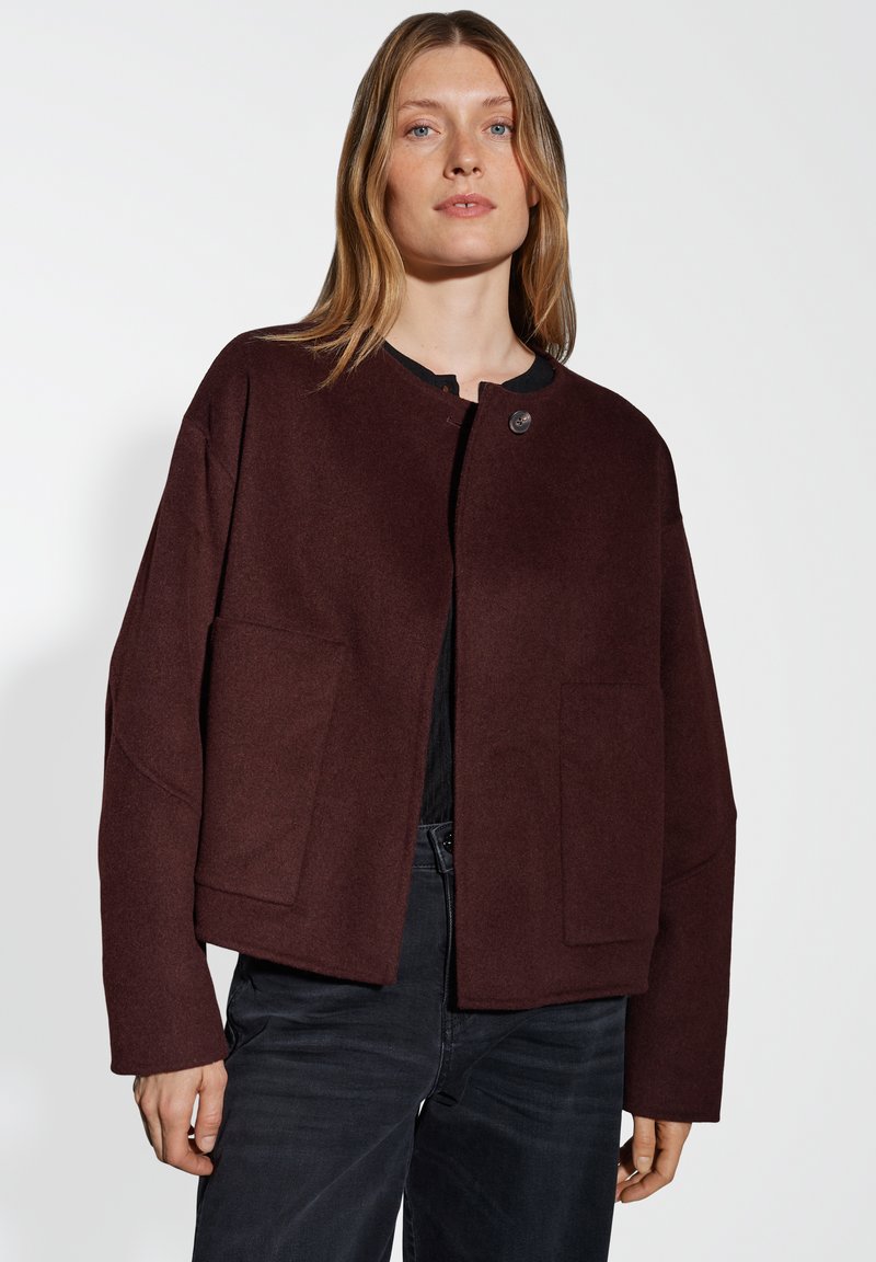 Bordeaux wollen blend jas met een ronde halslijn, twee voorzakken en een enkele knoopsluiting. Heeft een relaxte pasvorm en een geweven stof.