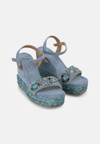 Sandali wedge in suede azzurro chiaro con una base intrecciata turchese e una cintura impreziosita con accenti blu e argento.