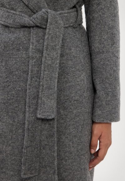 Grauester Wollmantel mit strukturierter Oberfläche, ausgestattet mit einem gebundenen Gürtel und langen Ärmeln. Der Stoff wirkt weich und warm.