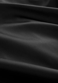 Tissu noir lisse avec de doux plis et une finition mate, montrant une texture subtile et des reflets de lumière.