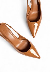 Brūni lakuoti sērfošanas apavi ar norādītu pirkstu un spīdīgu apdari, ar izliekta izgriezuma detaļām sānos un gludu iekšpusi.