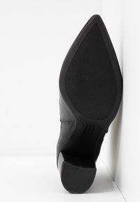 Pump in pelle nera con punta affusolata, suola texturizzata e tacco conico. Taglia marcata come 37. Finitura liscia con dettagli di cucitura minimi.