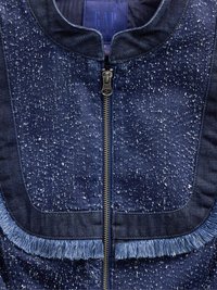 Giacca in denim scuro con motivo a macchie, dotata di zip frontale, colletto arrotondato e dettagli frangiati lungo il bordo inferiore.