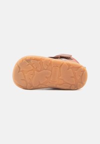 Scarpa in suede marrone con suola in gomma beige decorata con un motivo a foglia. Chiusura con cinturino regolabile per una vestibilità sicura. Taglia 22.