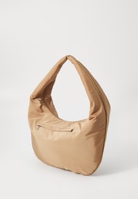 Nylon hobo-väska i beige med en slät yta, strukturerad form och en ficka med dragkedja fram. Har ett enda, runt axelband.