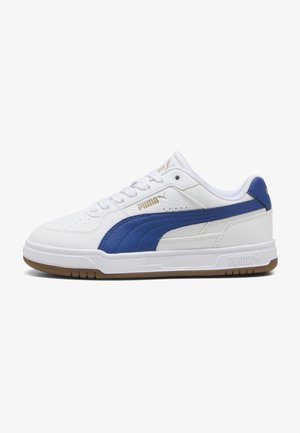 Białe niskie sneakersy Puma z niebieskim paskiem, złotym logo Puma, białymi sznurowadłami i gumową podeszwą, pokazane z profilu bocznego.