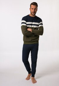 Suéter en azul marino y verde oliva, con franjas horizontales blancas, combinado con pantalones jogger azul marino con bolsillos. Textura de tela suave.