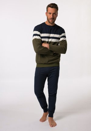 Pull en bleu marine et vert olive, avec des rayures blanches horizontales, associé à un pantalon de jogging bleu marine avec poches. Texture de tissu douce.