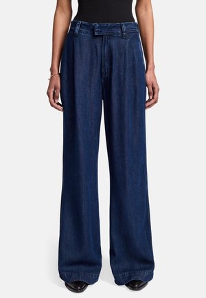 Jeans in denim scuro a gamba larga con vita alta, dotati di chiusura con bottone e passanti per cintura, texture liscia con una leggera lucentezza.