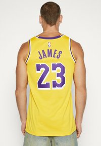 Maglia da basket gialla con rifiniture viola, con il nome "JAMES" e il numero "23" ben visibili sul retro.