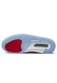 Semelle de chaussure en caoutchouc bleu translucide, avec des accents circulaires rouges et des sections texturées blanches et grises ; présente le logo 'JORDAN' de manière proéminente.