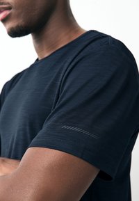 Navyblaues Sport-T-Shirt mit strukturiertem Stoff, Rundhalsausschnitt und kurzen Ärmeln mit reflektierendem Akzent am linken Arm.