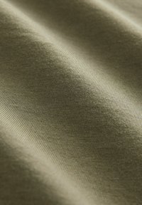 Olivgrüner Stoff mit glatter Textur, der ein feines Rippmuster aufweist. Die Oberfläche erscheint weich und leicht reflektierend im natürlichen Licht.
